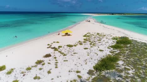 Aerial-shot-Caribbean-summer-Getaway,-beach-umbrellas-on-white-sand-stunning-scenic-cayo-de-agua-island