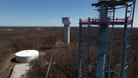 An-aerial-view-of-a-water-tower-being-dismantled-on-a-sunny-day-on-Long-Island,-New-York