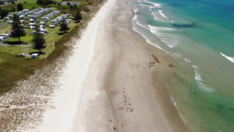 Campervans-parked-beside-Papamoa-Beach,-holiday-spot-during-summer-day