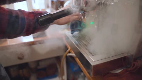 Barista-cleans-steam-wand-of-coffee-machine-with-cloth-and-steam
