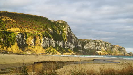 Pūrākaunui-settlement-in-Otago,-in-the-South-Island-of-New-Zealand-panoramic-view-of-ocean-beach-with-natural-stream-water-river-and-scenic-cliff-formation
