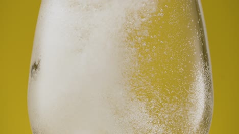 Nahaufnahme,-Die-Eine-Brausetablette-In-Ein-Klares-Wasserglas-Vor-Gelbem-Hintergrund-Wirft