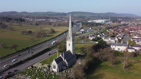 An-aerial-view-of-the-marble-church-in-Bodelwyddan-on-a-sunny-morning,-flying-left-to-right-around-the-church-while-zooming-out,-Denbighshire,-North-Wales,-UK