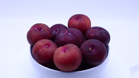 Fresh-plums-in-a-bowl-isolated-on-white-background