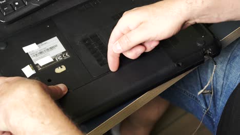 Repair-of-an-old-laptop,-the-technician-removes-the-battery-from-the-device