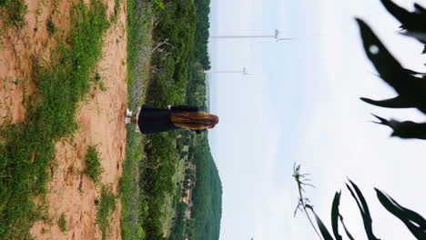 A-long-haired-girl-enjoying-the-scenic-windmill-farm-view-in-cloudy-weather