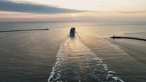 Cruise-liner-departing-harbor-sails-into-the-sunset-over-the-North-Sea,-aerial