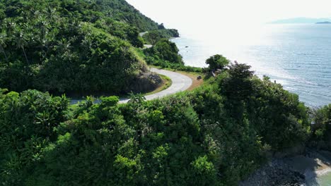 Aerial-Orbit-of-winding-cliffside-road-on-tropical-Philippine-island-facing-stunning-ocean-waters