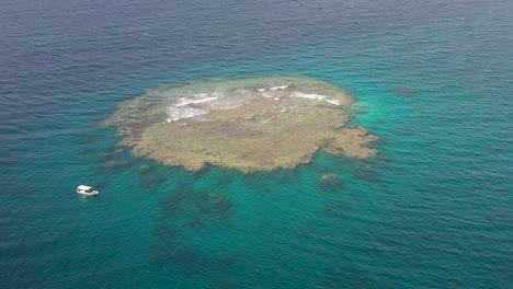 Scuba-dive-tour-boat-anchors-off-large-reef-island-in-red-sea-jeddah-saudi-arabia,-aerial-orbit