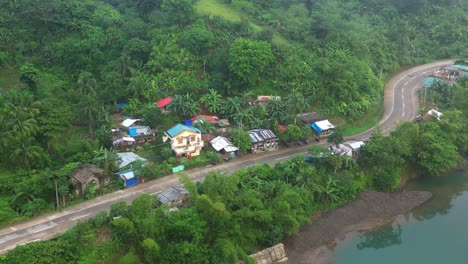 Kleines-Dorf-An-Der-Straße-Am-Berghang-Mit-Fließendem-Fluss-In-Der-Nähe-Der-Landschaft-In-Catanduanes,-Philippinen