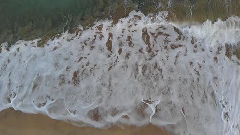Aerial-vertical-view-of-Matadouro-beach-and-waves-breaking-on-seashore