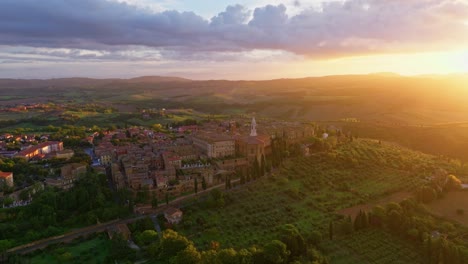 Aerial-at-sunset-over-the-Tuscany-landscape-with-the-city-of-Pienza-at-the-top-of-the-hill,-Province-of-Siena,-Italy