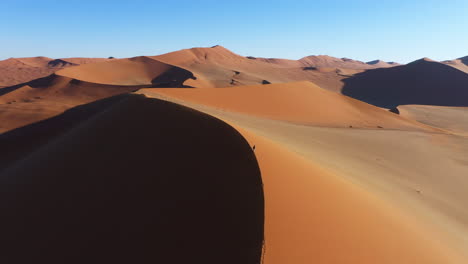 Aerial-view-around-a-person-on-top-of-a-sunny-dune-in-a-large-desert-landscape