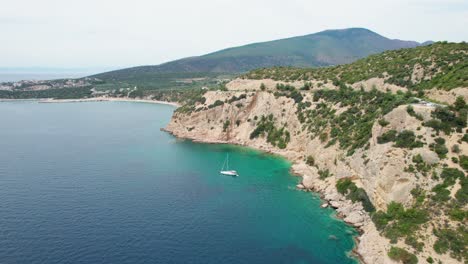Top-Down-View-Over-A-Rocky-Seaside,-Anchored-Sail-Boat,-Turquoise-Water,-Lush-Vegetation,-Fari-Beach,-Thassos-Island,-Greece