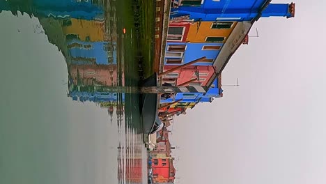 Unusual-low-angle-panoramic-view-of-Burano-colorful-houses-seen-from-canal-center,-Italy
