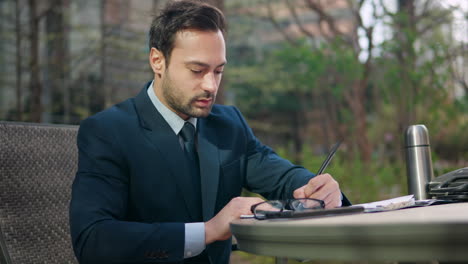 Businessman-signing-some-urgent-papers-in-a-park-near-office-building-during-lunch-break