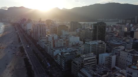 Sunset-at-Rio-de-Janeiro,-Arpoador,-with-buildings-and-mounts-backlit---aerial-shot