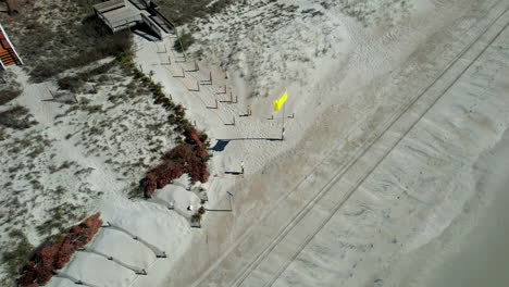 Drone-shot-of-yellow-flag-flying-at-the-beach,-aerial-shot