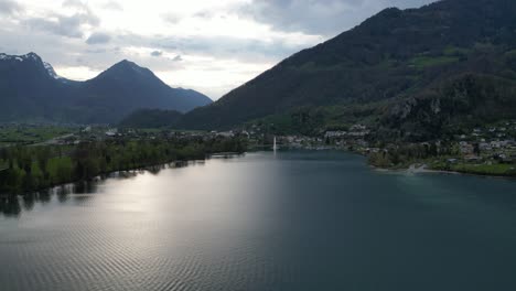 Aerial-view-of-magnificent-fountain-in-calm-Walensee-lake-with-Swiss-backdrop