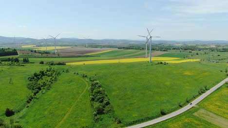 Wind-turbines-at-work,-renewable-energy-source-in-rural-landscape,-farmland-aerial-view