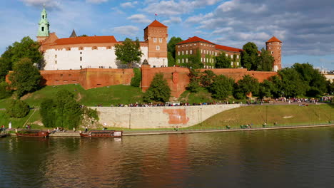 Drone-footage-of-Wawel-Royal-Castle-with-tourists-at-golden-hour,-Krakow,-Poland