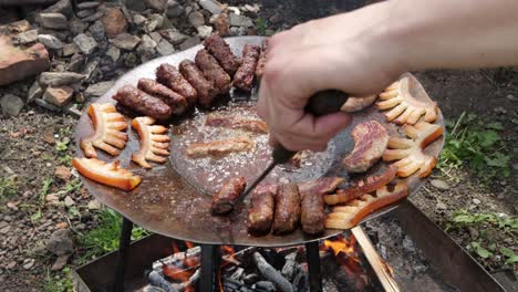 Person-grilling-Romanian-meat-rolls,-Mititei,-in-fat-from-slanina-over-wood-fire