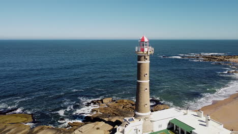 Steady-aerial-shot-of-lighthouse-with-ocean-and-coastline-in-background