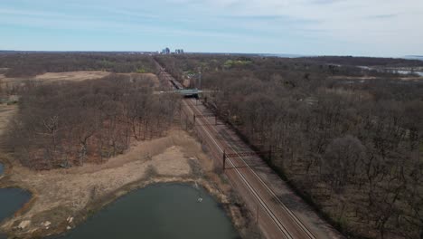 An-aerial-view-of-a-train-traveling-off-into-the-distance-in-the-Bronx,-New-York-on-a-sunny-day