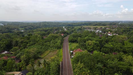 Drone-view-following-train-tracks-through-tropical-countryside-in-Indonesia