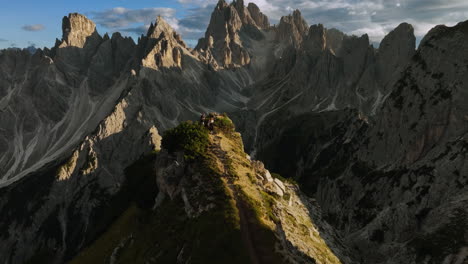 Aerial-view-tilting-over-people-at-the-Cadini-di-Misurina-viewpoint,-golden-hour-in-Dolomites,-Italy