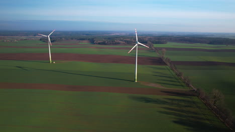 Aerial-panoramic-shot-of-rotating-wind-turbines-on-agricultural-fields-during-sunny-day