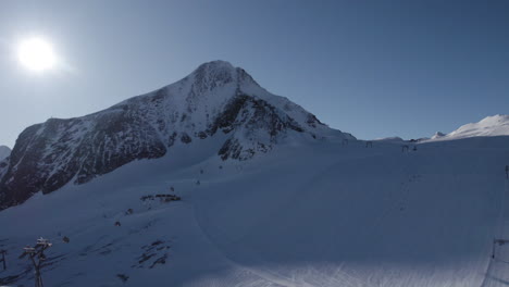 Ascending-drone-shot-showing-gigantic-Kitzsteinhorn-Mountain-in-Austria-against-bright-sunshine-at-blue-sky