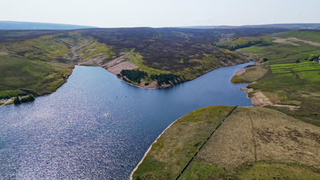 Winscar-reservoir-in-Yorkshire-hosts-a-captivating-boat-race-as-members-of-a-sailing-club-navigate-their-one-man-boats-through-the-tranquil-blue-lake,-guided-by-the-radiant-midday-sunlight