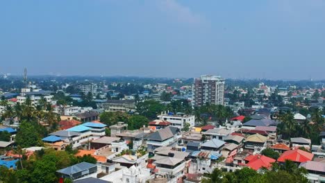 Aerial-view-of-Kochi,-a-city-in-India-,-Dwelling-houses-consisting-of-terraced-houses-,-Tanks-placed-above-houses-for-drinking-water-supply-,-A-skyline-of-a-growing-city-and-a-mobile-tower