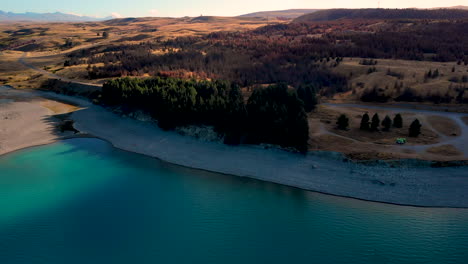 Lake-Pukaki-aerial-reveal-of-shore,-forest-and-beautiful-landscape,-New-Zealand