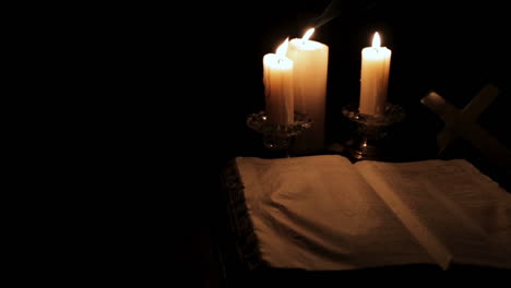 Die-Heilige-Bibel,-Beleuchtet-Von-Kerzenlicht-An-Einem-Versteckten,-Dunklen-Ort:-Schwenk-Nach-Rechts