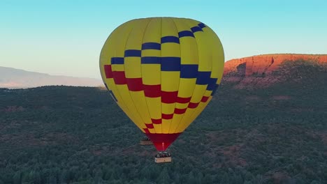 Colorful-Hot-Air-Balloon-Rising-In-Blue-Sky-In-Sedona,-Arizona---aerial-drone-shot