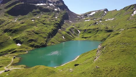 Antena-Empujando-Sobre:-Colores-De-Verano-Del-Lago-Alpino-Bachalpsee-En-Lo-Alto-De-La-Cordillera-De-Los-Alpes-Suizos-De-Grindelwald,-Suiza