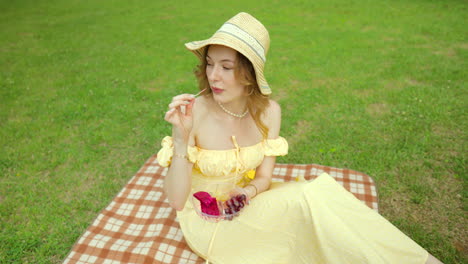 Mujer-Joven-En-Vestido-Amarillo-Disfrutando-De-Un-Picnic-En-El-Parque-Comiendo-Fruta-Y-Leyendo