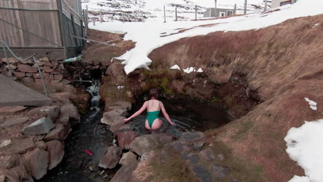 Mujer-Joven-Entrando-En-La-Piscina-Natural-De-Aguas-Termales-Durante-El-Invierno,-Islandia