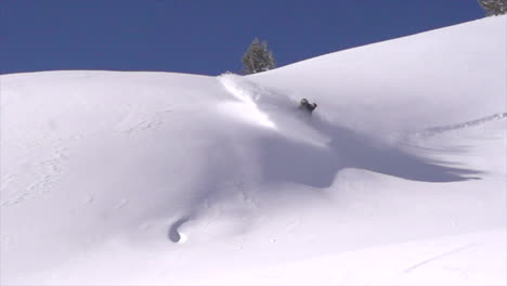 Male-Snowboard-bank-powder-turn-backcountry-powder-slow-motion-cinematic-mid-winter-fresh-snow-blue-skies-Colorado-at-Vail-Pass-early-morning