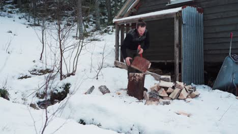 Man-Cutting-Wood-With-An-Axe-On-Winter-Countryside