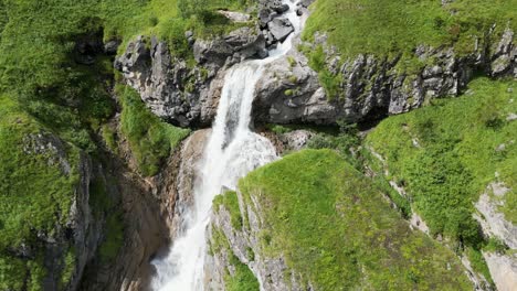 Waterfall-flowing-in-a-green-landscape,-clear-water-from-the-glacier-flowing,-Swiss-alps,-Obwald,-Engelberg,-drone-mavic-aerial-view