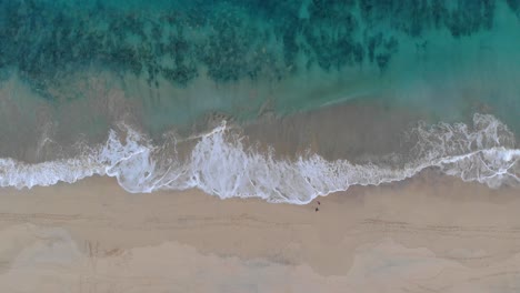 Luftaufnahme-über-Zwei-Menschen,-Die-Am-Sandstrand-Spazieren-Gehen,-Und-Wellen,-Die-Sich-Am-Meeresufer-Brechen