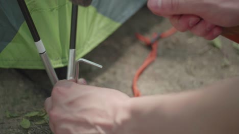 [CLOSE-UP]-shot-of-someone-pounding-a-tent-peg-into-dirt