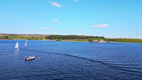 Winscar-Reservoir,-a-picturesque-blue-lake-in-Yorkshire,-where-sailing-boats-with-white-sails-glide-gracefully-across-the-calm-waters