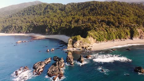 Drohne-Fliegt-über-Die-Von-Türkisblauem-Meer-Umgebenen-Felsen-Nahe-Der-Küste-In-Monroe-Beach,-Neuseeland---Luftaufnahme