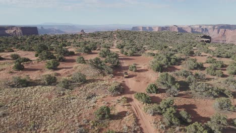 Aerial-Mustard-4x4-vehicle-crossing-canyon-landscape-in-Moab,Utah
