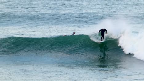 Surfer-Mit-Weißem-Helm-Fängt-Welle-Am-Strand-Und-Macht-Einen-Tollen-Carver