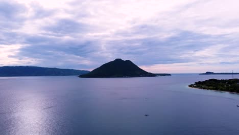 Aerial-drone-of-remote-tropical-island-within-a-colourful-hazy-cloudy-sunset-in-Alor-Island,-East-Nusa-Tenggara,-Indonesia
